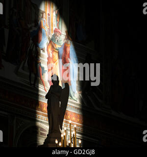 Statua di un angelo di fronte parzialmente illuminata opera su una parete; Firenze, Italia Foto Stock