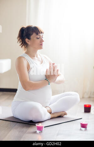 Gravidanza sana Yoga e fitness. Giovani incinta Donna yoga riposo dopo allenamento nel salotto. Modello di gravidanza seduta croce Foto Stock