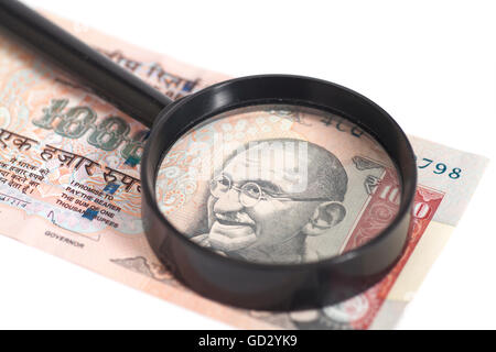 La valuta indiana rupia nota con lente di ingrandimento isolati su sfondo bianco Foto Stock