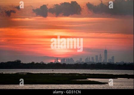 Manhattan come visto dalla Giamaica Bay, un rifugio della fauna selvatica che giace tra Brooklyn e Queens, al tramonto nei primi giorni di luglio. Foto Stock