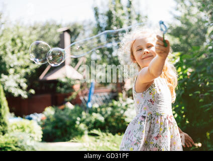 Carino bambina sta soffiando una bolle di sapone e divertirsi Foto Stock