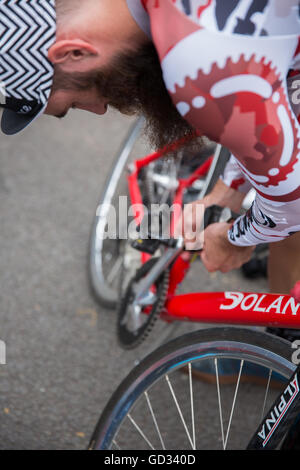 Un uomo barbuto ciclista che fissa la sua bici a Red Hook criterium in London Greenwich Peninsula prima della Red Hook Criterium Cy Foto Stock