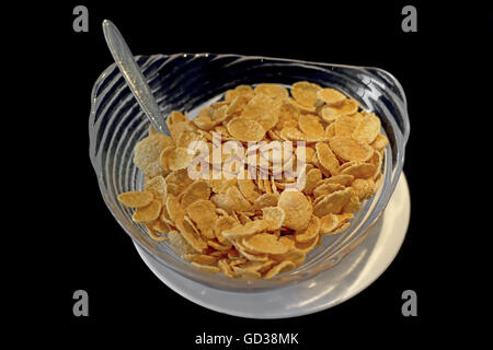 Cereali fiocchi di mais in una ciotola di vetro su sfondo nero Foto Stock