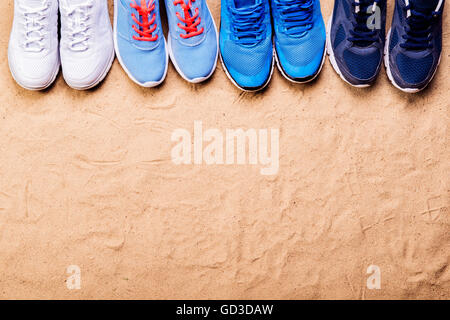 Vari sport scarpe in una fila contro la sabbia, studio shot Foto Stock