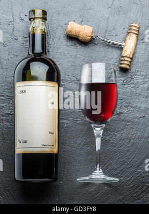 Bottiglia di vino, bicchiere di vino e un cavatappi sulla scheda di grafite. Foto Stock