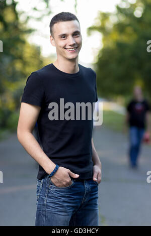 Giovane uomo caucasico nei primi 20s in posa sorridente. Profondità di campo. Foto Stock