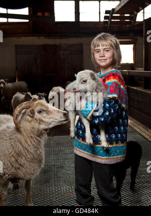 Giovane ragazza tenendo un giovane agnello, Borgarfjordur, Islanda Foto Stock
