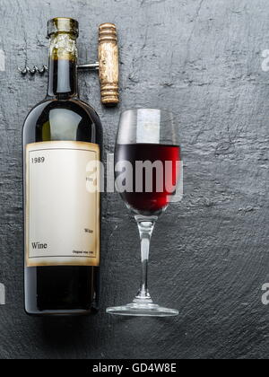 Bottiglia di vino, bicchiere di vino e un cavatappi sulla scheda di grafite. Foto Stock
