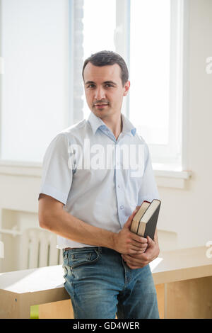 Ritratto di giovane azienda libri, guardando la fotocamera Foto Stock