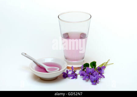 Sciroppo di violetta, ciotola e vetro, fiori viola Foto Stock