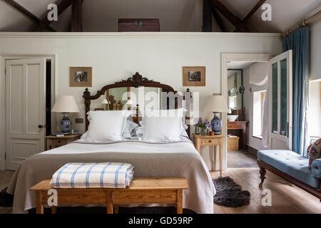 Blue abbottonata chaise longue in camera da letto con letto in mirroring di testa e stuoia di pelle di pecora Foto Stock