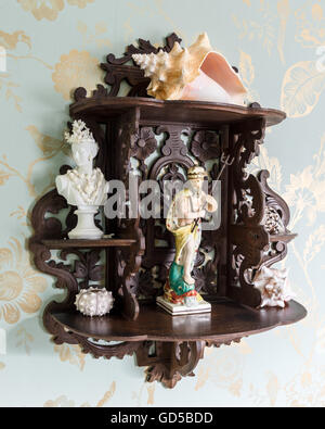 Staffordshire figure e conchiglie decorative su scaffale portautensili con Colefax & Fowler sfondo carta da parati Foto Stock