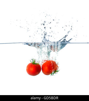 Rosso di frutti di pomodoro che affonda in acqua isolati su sfondo bianco Foto Stock