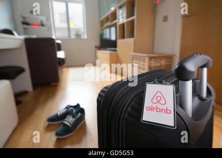 Una valigia con un marchio Airbnb etichetta bagaglio si siede in un appartamento a noleggio tramite il marketplace online (solo uso editoriale). Foto Stock