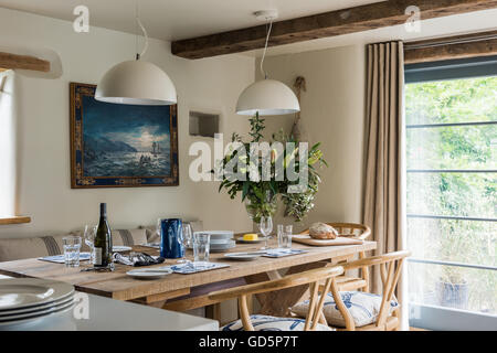 Rovere antico sedie da pranzo intorno a tavola in legno rustico prevista con la vetreria e piastre Foto Stock