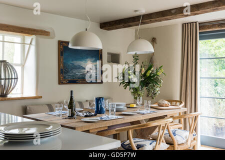 Rovere antico sedie da pranzo intorno a tavola in legno rustico prevista con la vetreria e piastre Foto Stock