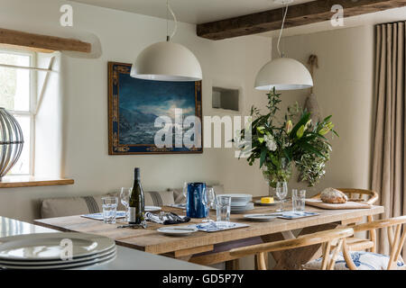 Rovere antico sedie da pranzo intorno a tavola in legno rustico prevista con la vetreria e piastre Foto Stock