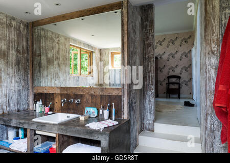 In cemento lucidato vanity in bagno con pareti rivestite con riciclata tavoloni Foto Stock