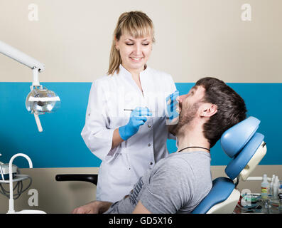 Medico esamina la cavità orale su carie. Protezione della carie. La carie di trattamento. Dentista lavora con polimerizzazione dentale lampada nella cavità orale Foto Stock