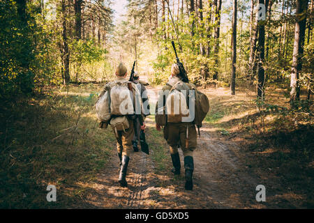 Due Unidentified Re-Enactors vestita come la II Guerra Mondiale russo soldati sovietici in camuffamento passeggiate attraverso la foresta sulla strada Foto Stock