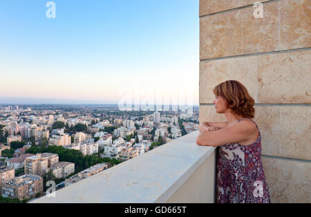 Donna su un balcone nel centro della città moderna Foto Stock