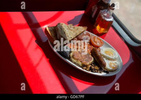La completa prima colazione inglese è servita sul double decker bus cafe. Hastings. East Sussex, Inghilterra. Regno Unito Foto Stock