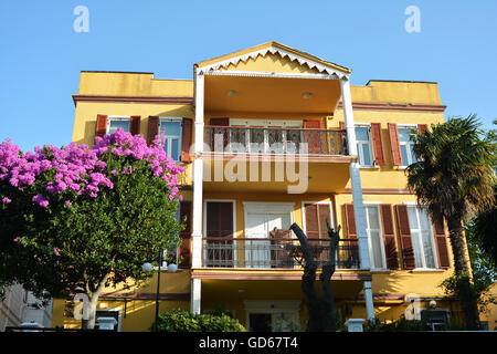 Verniciato giallo casa con balconi e colonne Foto Stock