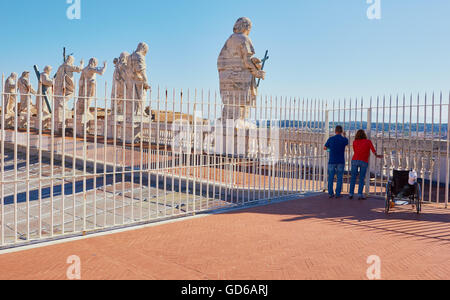 I turisti con sedia a rotelle e 13 statue in travertino di Cristo, san Giovanni Battista e di undici apostoli, Basilica di San Pietro Roma Lazio Italia Europa Foto Stock