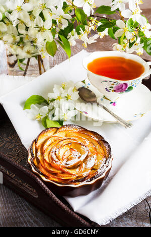 Apple a forma di rosa torta e tazza di tè sul servire vassoio. In casa torta di mele per il tè in tempo. Colazione tè con dolci pastr apple Foto Stock