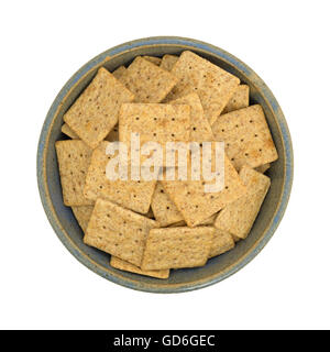 Vista dall'alto di un vecchio recipiente di ceramica riempito con organici cracker integrali isolato su uno sfondo bianco. Foto Stock