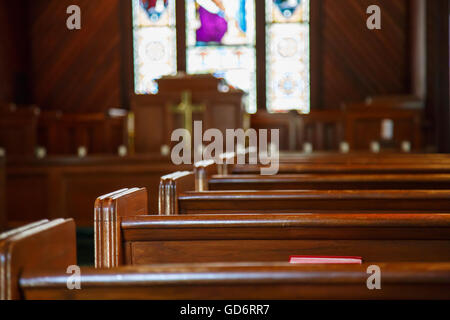 Le finestre di vetro macchiate nella piccola chiesa con le panche di legno Foto Stock