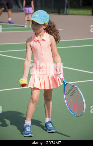 Una bambina gioca a tennis su un tribunale aperto Foto Stock