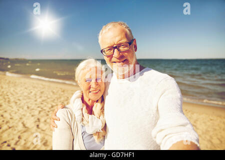 Gli anziani di scattare una foto con la bacchetta selfie sulla spiaggia Foto Stock