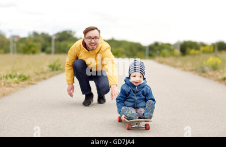 Felice padre e figlio a cavallo su skateboard Foto Stock