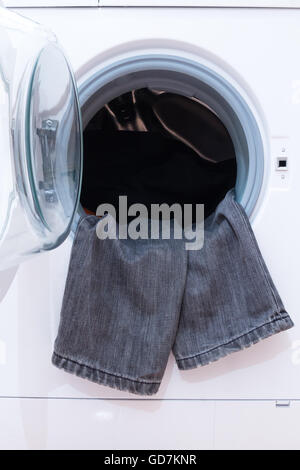 Una chiusura di una macchina di lavaggio caricata con i vestiti. Elettrodomestico. Foto Stock