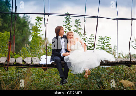 Sposa e lo sposo seduto su un ponte Foto Stock