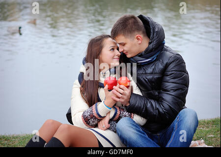 Giovane su uno sfondo di acqua in autunno con le mele Foto Stock