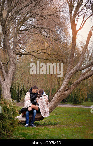 Uomo e donna che cammina in autunno park coperto con una coperta Foto Stock