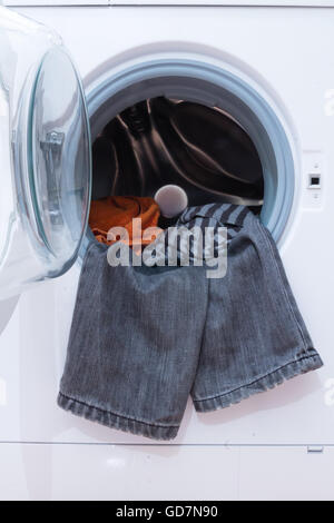 Una chiusura di una macchina di lavaggio caricata con i vestiti. Elettrodomestico. Foto Stock