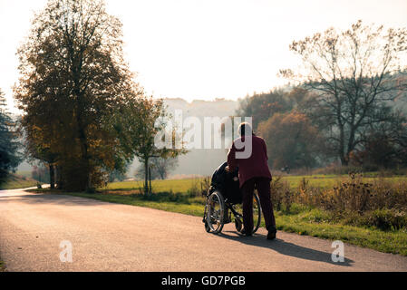 Disabili uomo senior e assistente nel parco Foto Stock