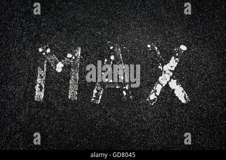La parola 'max', usurate e sbiadita, dipinta in bianco su una strada asfaltata Foto Stock
