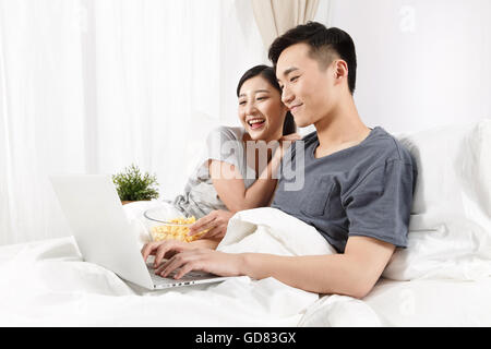 Coppia giovane seduto sul letto di vedere il computer Foto Stock