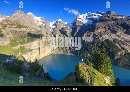 Escursionista ammira il lago Oeschinensee Oberland Bernese Kandersteg Cantone di Berna in Svizzera Europa Foto Stock