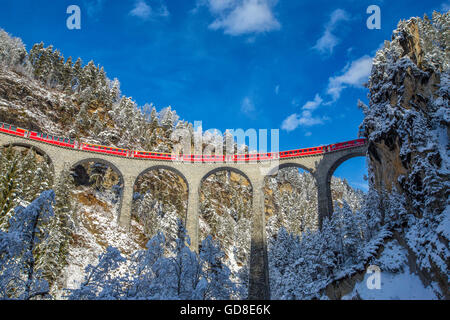 Bernina Express passa attraverso i boschi innevati intorno a Filisur Cantone dei Grigioni Svizzera Europa Foto Stock