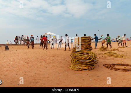 I pescatori non identificato a tirare le loro reti da pesca su Samudra Beach in Kovalam. Il Kerala. India Foto Stock