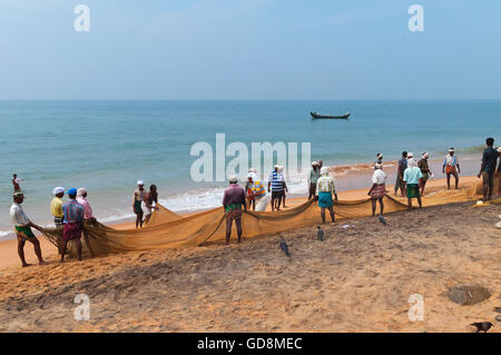 I pescatori non identificato a tirare le loro reti da pesca su Samudra Beach in Kovalam. Il Kerala. India Foto Stock