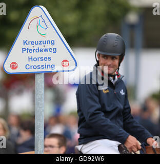 Aachen, Germania. 14 Luglio, 2016. Una lettura del segno "Kreuzung Pferdeweg - cavalli crossing' e un cavallo Cavaliere al torneo equestre chio di Aachen, Germania, 14 luglio 2016. Foto: Friso Gentsch/dpa/Alamy Live News Foto Stock