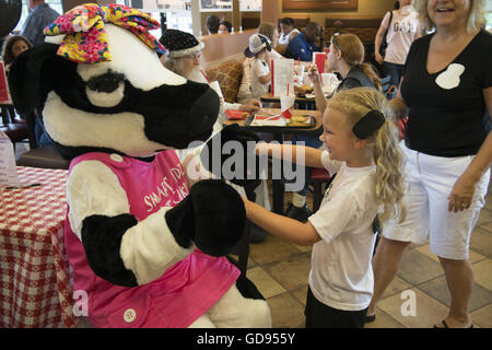 Duluth, GA, Stati Uniti d'America. 12 Luglio, 2016. Un giovane cliente gioca con la petite-Pulcino-fil-una vacca "Dolly" presso il ristorante sulla catena della "mucca apprezzamento giorno' © Robin Rayne Nelson/ZUMA filo/Alamy Live News Foto Stock