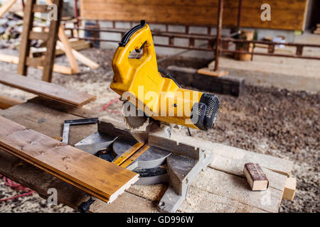 Sega circolare prevista sul tavolo, la pila di legno dietro di essa Foto Stock