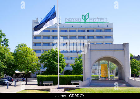 Bandiera estone sulla piazza principale di Pärnu con il monumento di indipendenza e hotel Pärnu in background Foto Stock